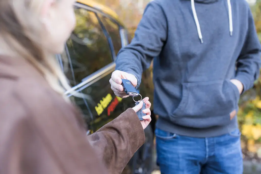 Fahrlehrer &uuml;bergibt Schl&uuml;ssel einer Sch&uuml;lerin