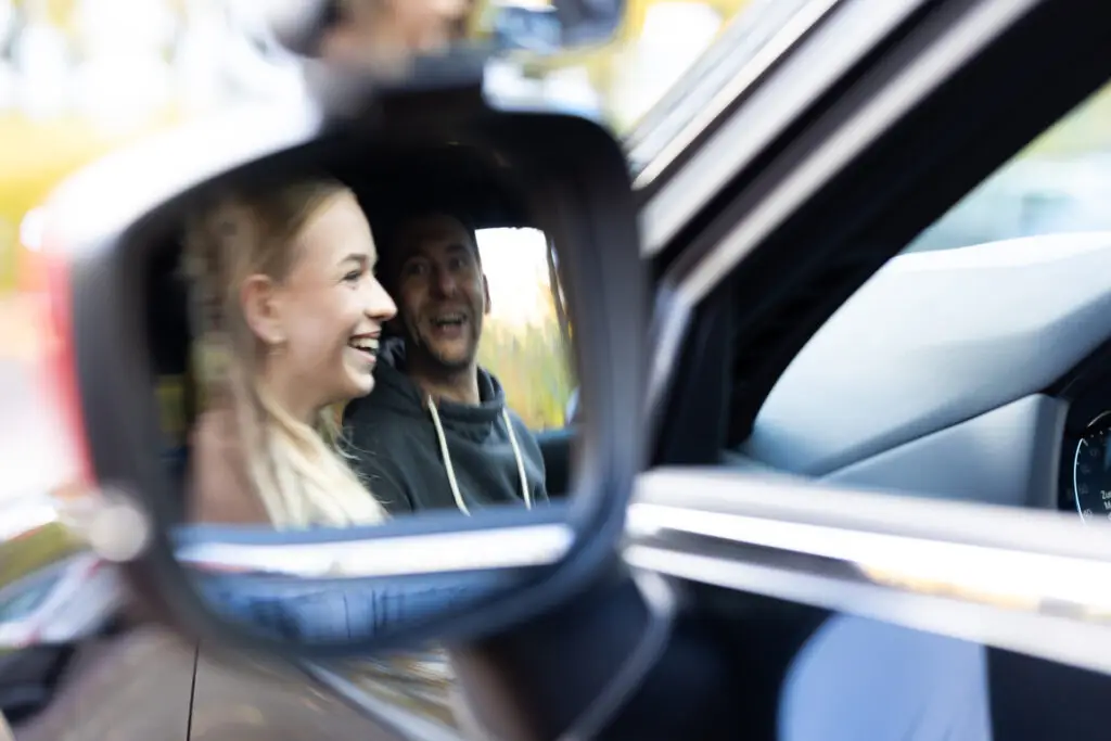 Fahrsch&uuml;lerin und Fahrlehrer der im Seitenspiegel des Fahrschulautos der Fahrschule Fehr